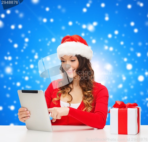 Image of smiling woman in santa hat with gift and tablet pc