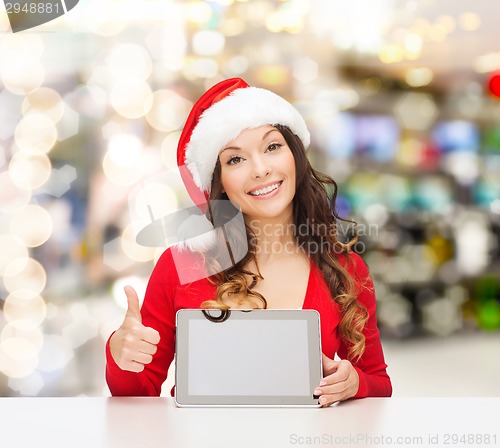 Image of smiling woman in santa hat with gift and tablet pc