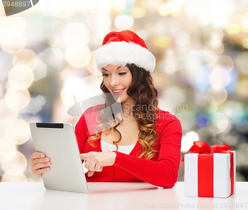 Image of smiling woman in santa hat with gift and tablet pc