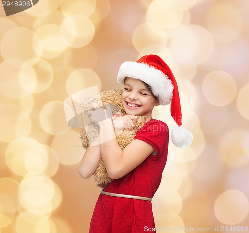 Image of smiling girl in santa helper hat with teddy bear