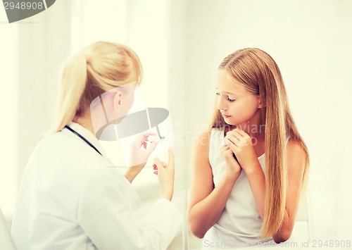 Image of doctor with child measuring temperature