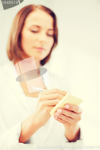 Image of businesswoman writing on sticky note