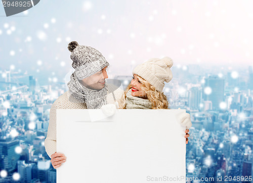 Image of smiling couple in winter clothes with white board