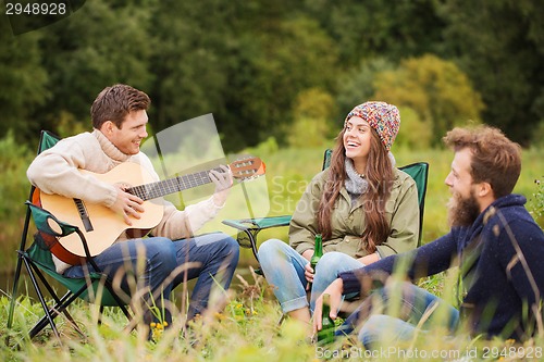 Image of group of smiling friends with guitar outdoors