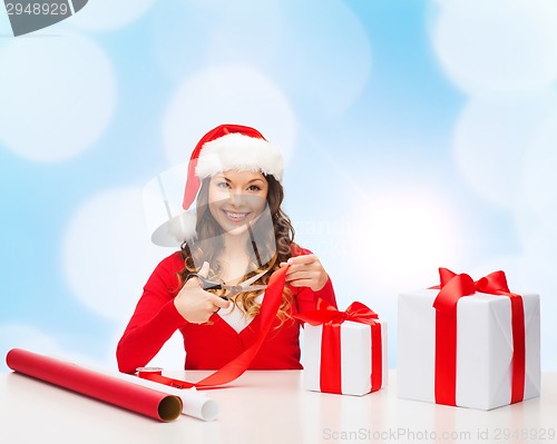 Image of smiling woman in santa helper hat packing gift box