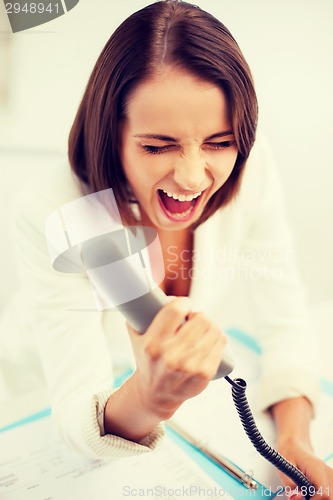 Image of woman shouting into phone in office