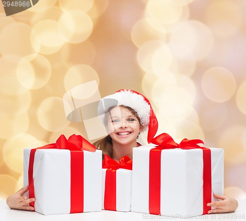 Image of smiling girl in santa helper hat with gift boxes