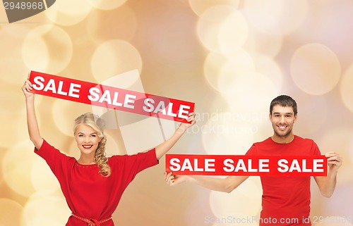 Image of smiling man and woman with red sale signs