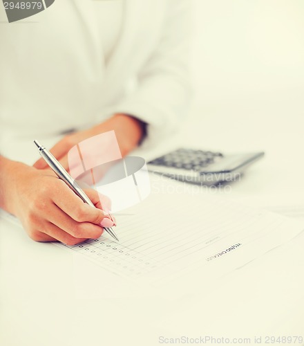 Image of businesswoman working with calculator in office