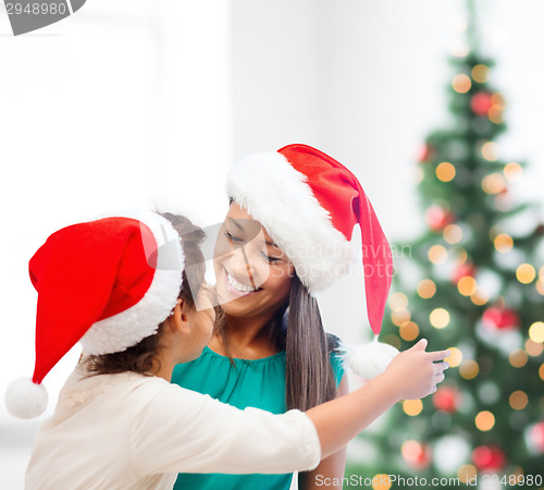 Image of hugging mother and daughter in santa helper hats