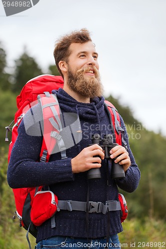 Image of smiling man with backpack and binocular outdoors