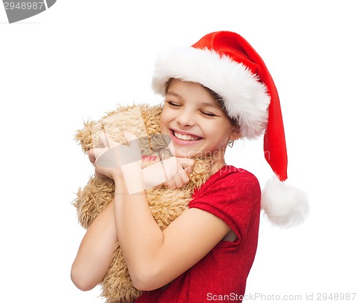 Image of smiling girl in santa helper hat with teddy bear