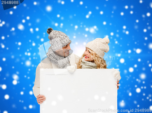 Image of smiling couple in winter clothes with white board