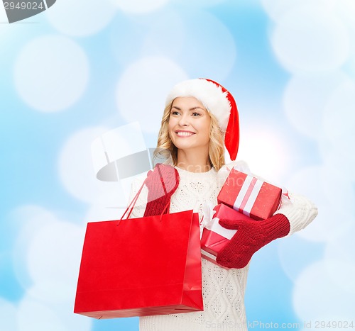 Image of smiling young woman in santa helper hat with gifts