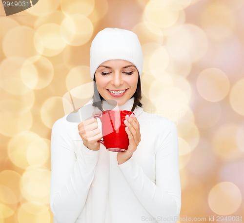 Image of smiling young woman in winter clothes with cup