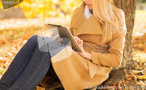 Image of young woman with tablet pc in autumn park