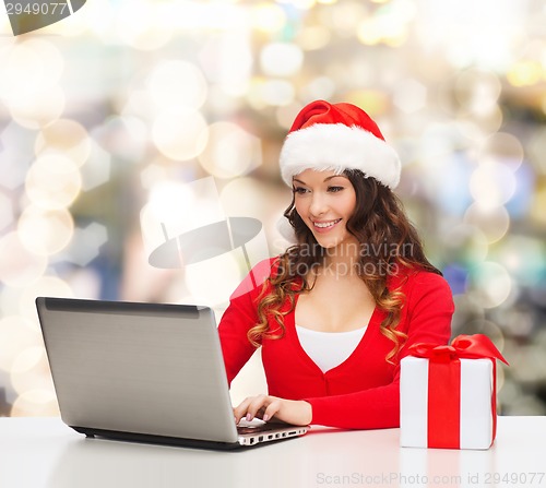 Image of smiling woman with gift box and laptop