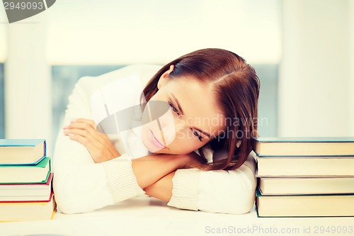 Image of tired student with books and notes