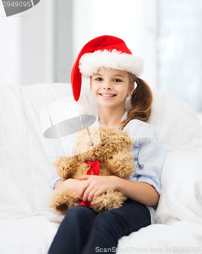 Image of smiling girl in santa helper hat with teddy bear