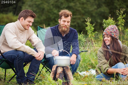 Image of group of smiling friends cooking food outdoors