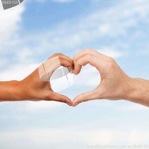 Image of woman and man hands showing heart shape