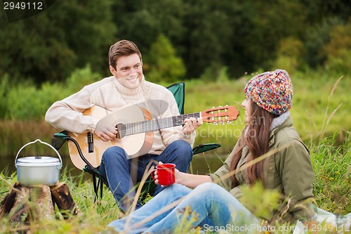 Image of smiling couple with guitar in camping