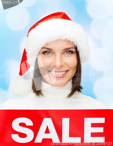 Image of smiling woman in santa helper hat with sale sign
