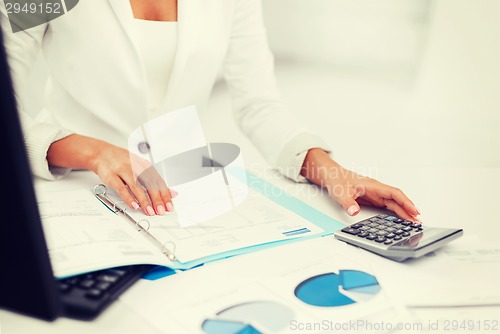 Image of woman hand with calculator and papers