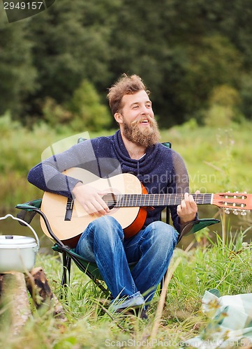 Image of smiling man with guitar and dixie in camping