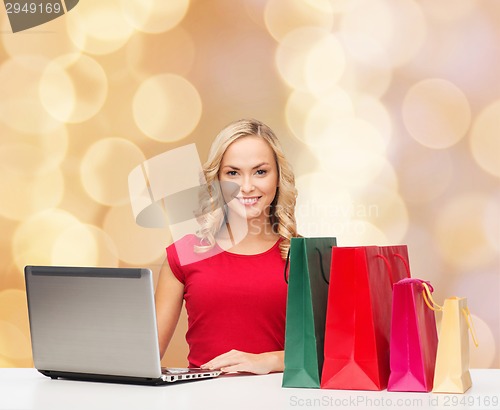 Image of smiling woman in red shirt with gifts and laptop