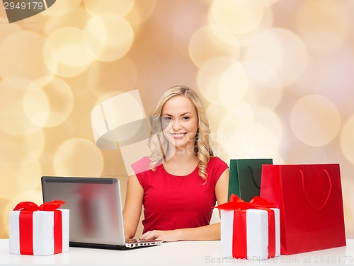 Image of smiling woman in red shirt with gifts and laptop