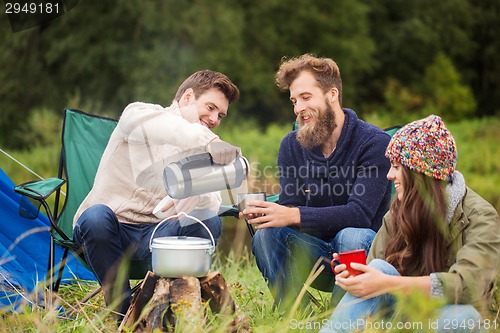 Image of group of smiling friends cooking food outdoors