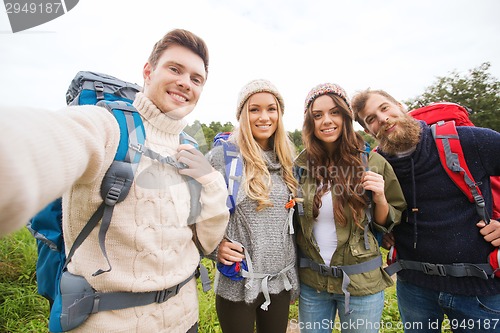 Image of group of smiling friends with backpacks hiking