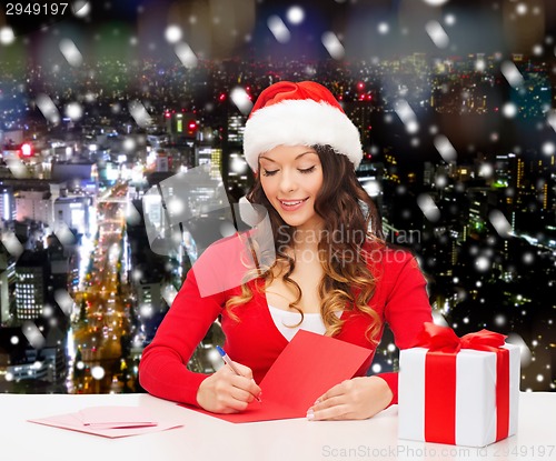 Image of smiling woman with gift box writing letter