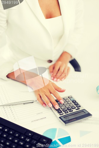 Image of woman hand with calculator and papers