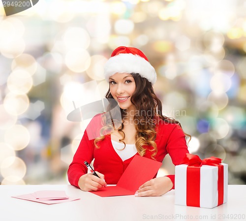 Image of smiling woman with gift box writing letter