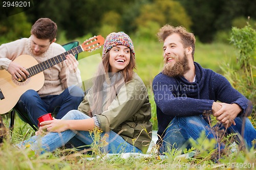 Image of group of smiling friends with guitar outdoors