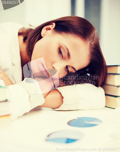 Image of bored young woman with many books and graphs