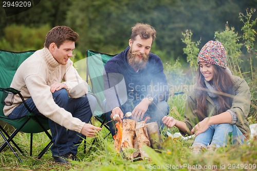 Image of group of smiling friends sitting around bonfire