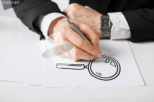 Image of close up of male hands with pen drawing lens