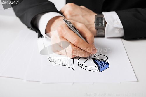 Image of close up of male hand with pen drawing graph