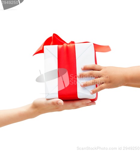 Image of close up of child and mother hands with gift box