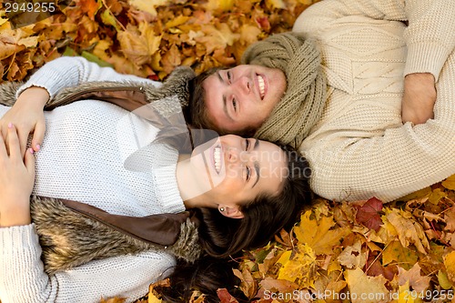 Image of close up of smiling couple lying in autumn park