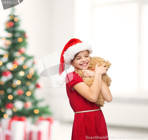 Image of smiling girl in santa helper hat with teddy bear