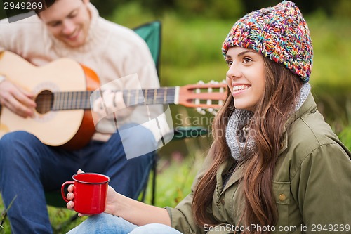 Image of smiling couple with guitar in camping