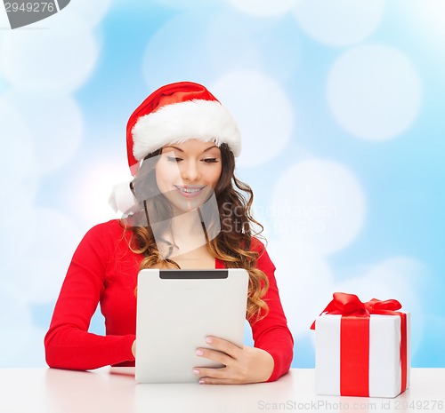 Image of smiling woman in santa hat with gift and tablet pc