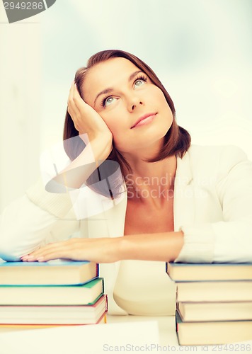 Image of bored young woman with many books indoors