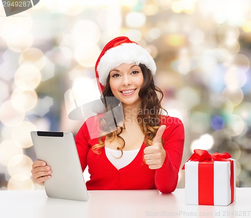 Image of smiling woman in santa hat with gift and tablet pc