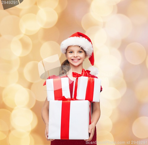 Image of smiling little girl in santa helper hat with gifts