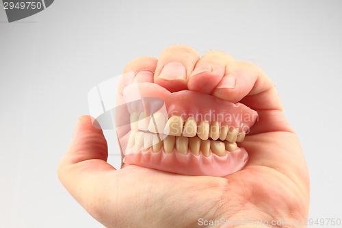 Image of teeth prosthesis in the human hand 